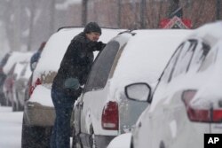 Seorang pengendara mobil membersihkan kendaraannya dari salju, Kamis, 3 Februari 2022, di Indianapolis. (Foto: AP/Darron Cummings)