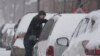 Un automovilista limpia de nieve su vehículo el jueves 3 de febrero de 2022, en Indianápolis, EE. UU.