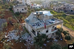 FILE - People inspect a destroyed house following a U.S. military operation in Atmeh, Syria, Feb. 3, 2022. Islamic State leader Amir Muhammad Sa'id Abdal-Rahman al-Mawla was killed in the raid.