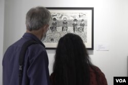 Visitors view one of Morn Chear's block print works during an exhibition at Shop House Studio, in Phnom Penh, February 2022.