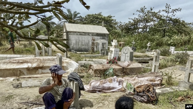 Relatives sit next to bodies exhumated from graves destroyed by Cyclon Batsirai at the local cemetery in Mahanoro, Madagascar, Feb. 6, 2022.