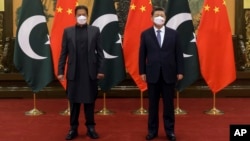 In this photo released by Xinhua News Agency, Chinese President Xi Jinping, right, and Pakistan Prime Minister Imran Khan pose for a photo before their bilateral meeting at the Great Hall of the People in Beijing, Feb. 6, 2022. 