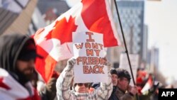 Seorang pendemo memegang poster yang bertuliskan, "Saya ingin kebebasan saya kembali," dalam aksi protes menentang mandat vaksin dan pembatasan terkait COVID-19 di Toronto, Kanada, pada 5 Februari 2022. (Foto: AFP/Geoff Robins) 