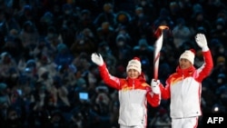 Chinese torchbearer athletes Dinigeer Yilamujian (L) and Zhao Jiawen hold the Olympic flame during the opening ceremony of the Beijing 2022 Winter Olympic Games, Feb. 4, 2022.