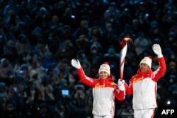 Atlet pembawa obor China, Dinigeer Yilamujian (kiri) dan Zhao Jiawen memegang api Olimpiade saat berlangsungnya upacara pembukaan Olimpiade Musim Dingin Beijing 2022, di Stadion Nasional, yang dikenal sebagai Sarang Burung, di Beijing, 4 Februari 2022. (Ben STANSALL / AFP)