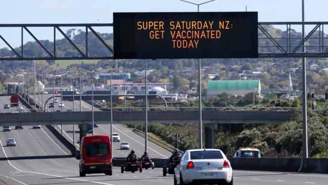 FILE - A sign on an Auckland motorway urges people to get vaccinated at a COVID-19 vaccination clinic during a single-day vaccination drive, in Auckland, New Zealand, Oct. 16, 2021.