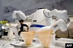 FILE - An attendant pours coffee as a robot makes a fresh pot in a waiting area within the closed-loop "bubble" at the Taizicheng train station in Zhangjakou on Jan. 29, 2022, ahead of the 2022 Beijing Winter Olympic Games.