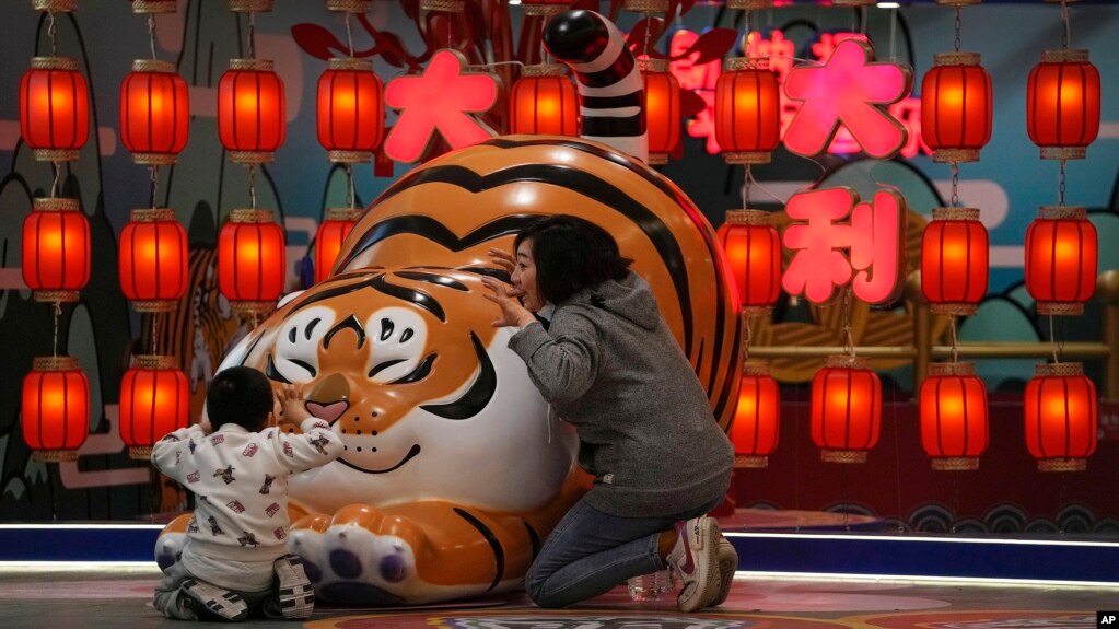 北京一家商场设立的卡通老虎迎接虎年春节，一对母子围着卡通老虎做游戏。（2022年1月9日）(photo:VOA)