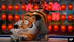 北京一家商場設立的卡通老虎迎接虎年春節，一對母子圍著卡通老虎做遊戲。 （2022年1月9日）