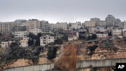 Pekerja membangun kembali bagian pembatas pemisah Israel antara Yerusalem dan desa A-Ram di Tepi Barat, setelah sebagian runtuh pekan lalu, Minggu, 6 Februari 2022. (AP Photo/Mahmoud Illean)