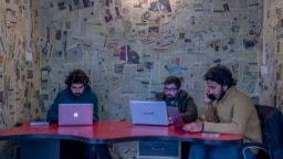 FILE- Fahad Shah, right, editor-in-chief of Kashmir Walla, works on his computer inside the newsroom at his office in Srinagar, Indian controlled Kashmir, Friday, Jan. 21, 2022. 