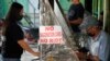 FILE - A woman stands beside a sign to remind passengers to show their vaccination card before riding at a jeepney terminal in Quezon city, Philippines on Jan. 17, 2022.