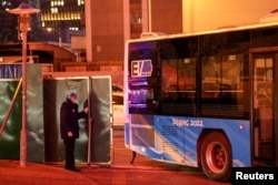 A security guard opens a gate to let in a bus inside the Olympic "closed-loop" in Beijing, China, Feb. 7, 2022.