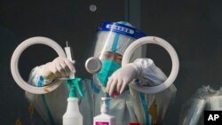 FILE - A medical worker wearing protective gear prepares swabs at a coronavirus test site in Xichen District in Beijing, Jan. 25, 2022. 