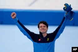 Nils van der Poel of Sweden celebrates his gold medal and Olympic record during a flower ceremony for the men's speedskating 5,000-meter race at the 2022 Winter Olympics, Feb. 6, 2022, in Beijing.
