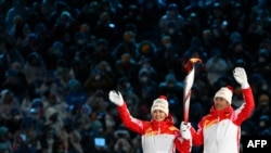 Atlet pembawa obor China Dinigeer Yilamujian (kiri) dan Zhao Jiawen memegang nyala api Olimpiade pada upacara pembukaan Olimpiade Musim Dingin Beijing 2022, di Stadion Nasional, Beijing, China, 4 Februari 2022. (Ben STANSALL / AFP)