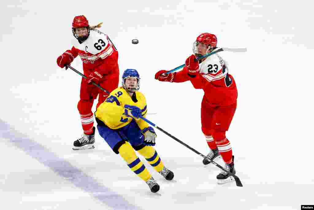 Jessica Adolfsson of Sweden go for the puck with Julie Oksbjerg of Denmark and Josefine Jakobsen of Denmark during the women&#39;s early round group B match of the 2022 Beijing Olympics ice hockey competition between Sweden and Denmark, at the Wukesong Sports Center.