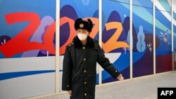 FILE - A member of Chinese security guides arriving passengers within the closed-loop "bubble" at the Taizicheng train station in Zhangjakou on Jan. 29, 2022, ahead of the 2022 Beijing Winter Olympic Games. 