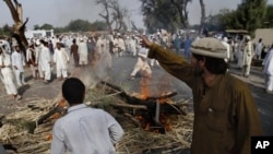 Afghan men from the Shinwari tribe stand near burning firewood set up as road blockade during a protest over a land dispute in Nangarhar province, east of Kabul, Afghanistan, August 10, 2011.