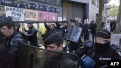 FILE - A migrant' supporter raises his hands as a policeman escorts him during a protest against the Jean-Jaurès highschool evacuation in Paris on May 4, 2016.