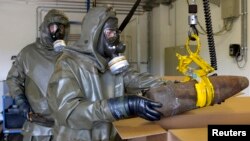 Trabajadores destruyen armas químicas en Siria.