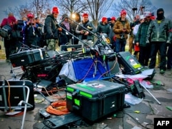 FILE - Supporters of U.S. President Donald Trump stand next to media equipment that was destroyed during a protest outside the Capitol in Washington, Jan. 6, 2021.