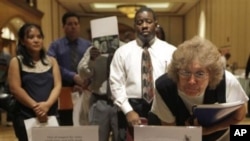 Vera Roybal, right, of Las Vegas, reads flyers at a temporary employment agency table during a job fair in Las Vegas, where unemployment rate is 14.7 percent, 05 Oct 2010