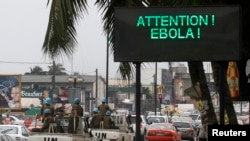 A U.N. convoy of soldiers passes a screen displaying a message on Ebola on a street in Abidjan, Aug. 14, 2014. Sebuah konvoi PBB melewati papan yang memperingatkan masyarakat akan penyebaran Ebola di Abidjan, Pantai Gading.