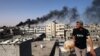 Seorang lelaki memperhatikan asap hitam yang tebal keluar dari gedung yang terbakar akibat serangan bom oleh Israel di Rafah, di bagian selatan Jalur Gaza, pada 10 Mei 2024. (Foto: AFP)