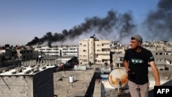 Seorang lelaki memperhatikan asap hitam yang tebal keluar dari gedung yang terbakar akibat serangan bom oleh Israel di Rafah, di bagian selatan Jalur Gaza, pada 10 Mei 2024. (Foto: AFP)