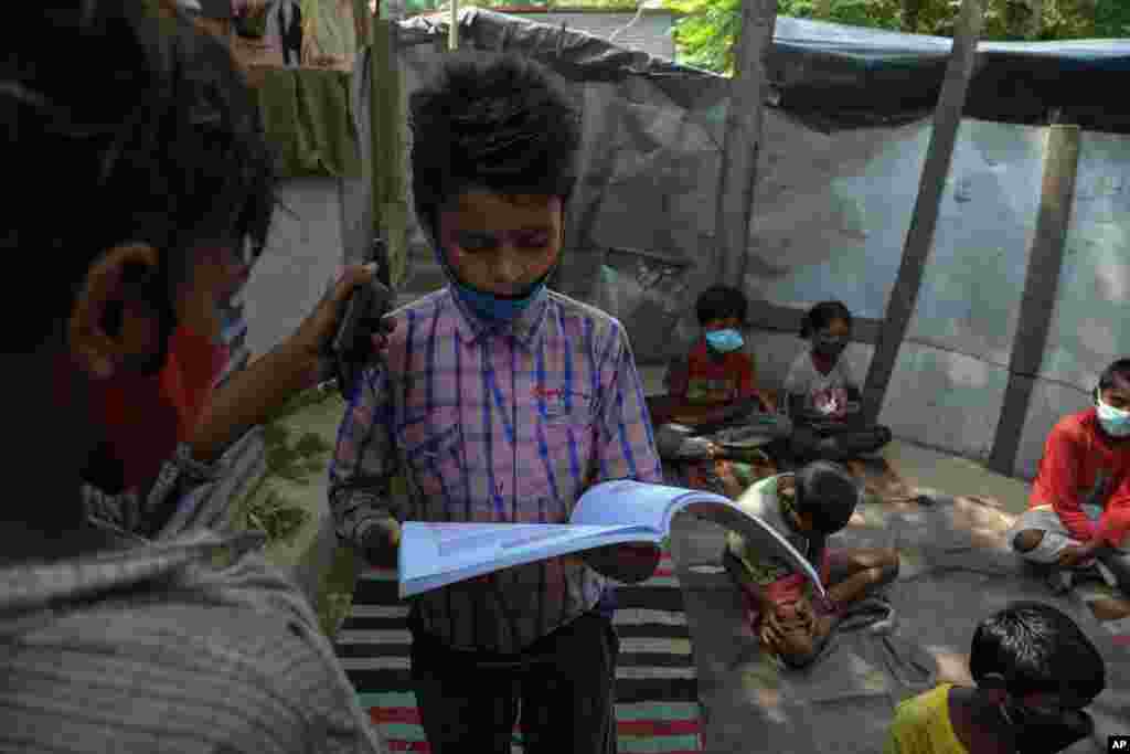 کمک یک دانش‌آموز به دانش‌آموز دیگر با گرفتن گوشی تلفن برای شنیدن صحبت‌های معلم آنلاین، در یک محله فقیرنشین در جامو، هند