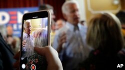 FILE - An attendee records former vice president and Democratic presidential candidate Joe Biden during a campaign event, June 4, 2019, in Berlin, New Hampshire.