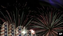 Banners with the United States flag colors wave as fireworks burst in the air during the Fourth of July Independence Day show at State Fair Meadowlands, in East Rutherford, N.J., July 3, 2012.