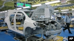 A worker walks past a Toyota Motor Yaris sedan at Central Motor Co's new factory in Ohira village, Japan, April 16, 2011