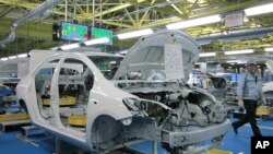 A worker walks past a Toyota Motor Yaris sedan at Central Motor Co's new factory in Ohira village, Japan, April 16, 2011