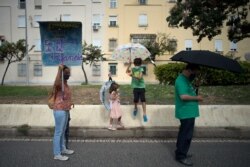 A woman holds a sign reading 'Public school: sustainable, free, active, in defense of children" as teachers and students take part in a protest calling for a 'safe education' in Malaga, Spain, Sept. 18, 2020.