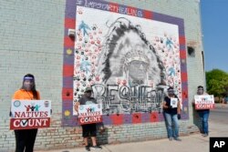 Activists hold signs promoting Native American participation in the U.S. census on the Crow Indian Reservation in Lodge Grass, Mont., Aug. 26, 2020