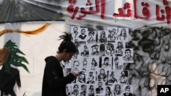 FILE - An anti-government protester checks his mobile phone in front of a wall of graffiti in Arabic that reads, "I am the revolution leader," in downtown Beirut, Lebanon, Nov. 21, 2019. 