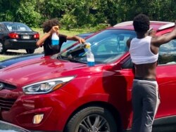 Baltimore’s so-called “squeegee kids” help teenagers make money by washing car windshields as drivers wait at stoplights. (VOA/C. Presutti)