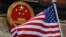 FILE - The American flag is flown next to the Chinese national emblem during a welcome ceremony for visiting U.S. President Donald Trump outside the Great Hall of the People in Beijing, Nov. 9, 2017. 