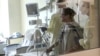 FILE - Coronavirus patient Joan Bronson walks across her hospital room with the help of a physical therapist at Ochsner Medical Center in the New Orleans suburb of Jefferson, La., Aug.11, 2021.