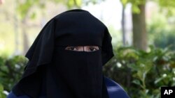 FILE - Selma, a 22 year old woman, wears the niqab as she sits in a park in Brussels, April 22, 2010. 