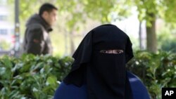 FILE - Selma, a 22 year old woman, wears the niqab as she sits in a park in Brussels.