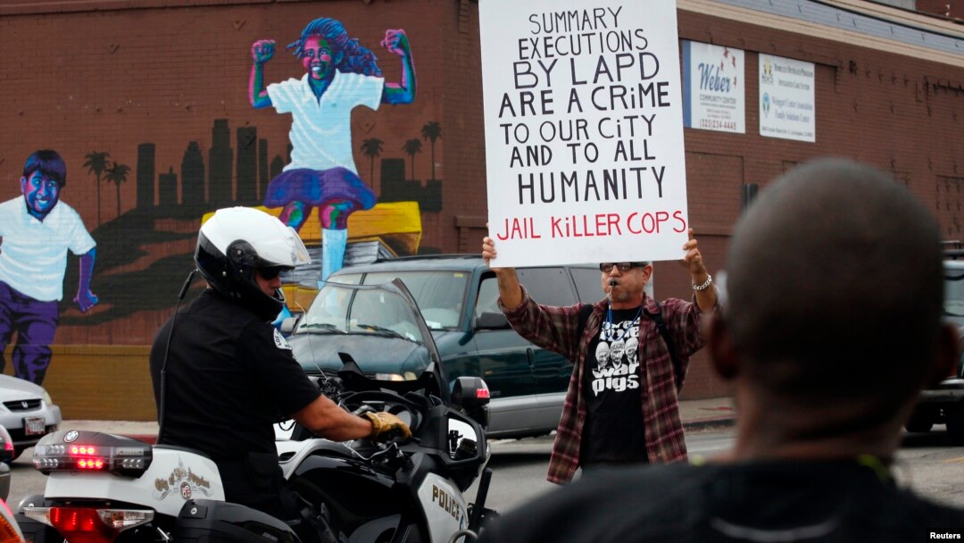 Seorang demonstran menghalangi polisi Los Angeles dalam protes atas penembakan fatal Ezell Ford, di Los Angeles (1/12).