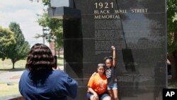 Katrina Cotton, centro de Houston, posa para una foto con su hija, Kennedy Cotton en el memorial de Black Wall Street en Tulsa, Oklahoma.