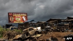 L'épave d'une voiture incendiée, qui aurait été détruite par des combattants séparatistes, est vue alors qu'un soldat camerounais (à gauche) patrouille au bord du marché abandonné dans la province à majorité anglophone du Sud-Ouest à Buea, au Cameroun, le 3 octobre 2018.