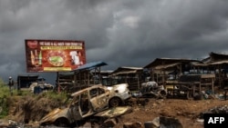 FILE - The wreckage of burnt car, allegedly destroyed by separatist fighters, is seen as a Cameroonian soldier (L) patrols the edge of the abandoned market in the majority Anglophone South-West province in Buea, Cameroon, Oct. 3, 2018. 