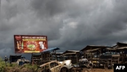 FILE - The wreckage of a burnt car, allegedly destroyed by separatist fighters, is seen as a Cameroonian soldier (L) patrols the edge of the abandoned market in the majority Anglophone South-West province in Buea, Cameroon, Oct. 3, 2018. 