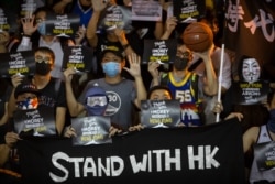 FILE - Demonstrators hold up signs in support of Houston Rockets general manager Daryl Morey during a rally at the Southorn Playground in Hong Kong, Oct. 15, 2019.