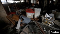 Documents, ballot boxes and debris are seen, as security personnel inspect the site of a suicide attack on the electoral commission in Tripoli, Libya, May 2, 2018.